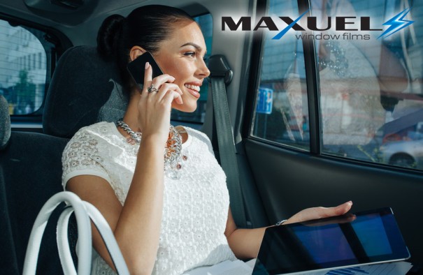 Young businesswoman talking on the phone in the back seat of the car and holding in hand a digital tablet